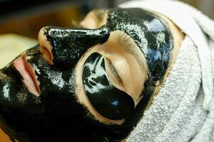 el cosmetóloga pone un máscara en el cara de un joven hombre. foto