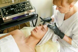 The cosmetologist makes the procedure ultrasonic face peeling photo