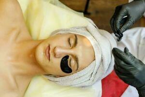 The cosmetologist puts a mask on the face of a young man. photo
