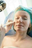 Doctor beautician makes injections in the forehead for patient. photo