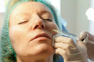 Doctor beautician makes injections in the forehead for patient. photo