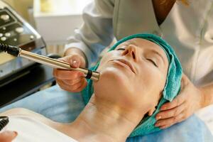 Cosmetologist makes the procedure microcurrent therapy in a beauty salon photo