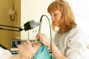 Cosmetologist makes the procedure microcurrent therapy in a beauty salon photo