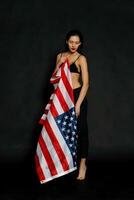Portrait female athlete wrapped in American Flag against black background photo