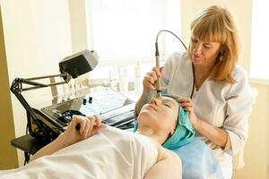 Cosmetologist makes the procedure microcurrent therapy in a beauty salon photo