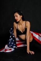 Portrait female athlete wrapped in American Flag against black background photo