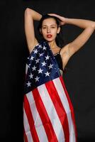 Portrait female athlete wrapped in American Flag against black background photo