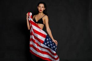 Portrait female athlete wrapped in American Flag against black background photo