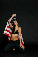 retrato hembra atleta envuelto en americano bandera en contra negro antecedentes foto