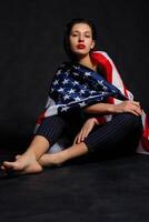 retrato hembra atleta envuelto en americano bandera en contra negro antecedentes foto