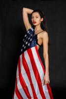 Portrait female athlete wrapped in American Flag against black background photo