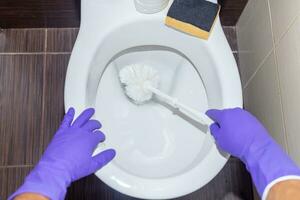 Man hand cleaning toilet with brush photo