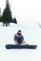 Snowboarder sitting at the top of a mountain photo