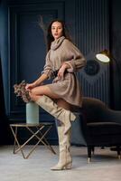 Young beautiful brunette woman in beige boots in a beautiful interior photo