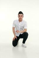 Handsome, young, trendy man is sitting on the floor in studio photo