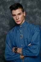 Man in denim shirt, arms on hips, gray background. photo