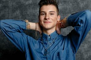 Man in denim shirt, arms on hips, gray background. photo