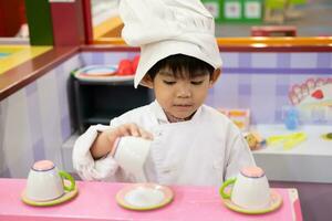 pequeño asiático chico jugando cocinero servicio comida foto