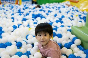 A little Asian boy was playing hide-and-seek among the balls. photo