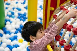 A little boy practices climbing a rope net in the play park. photo