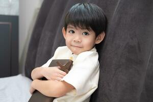 Little Asian boy prays holding a cross and a religious book, Christian concept photo