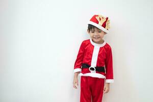 Asian boy wearing Santa costume Standing and playing near A fun Christmas tree on white background. photo