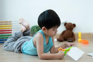 Asian boy using scissors to cut paper along lines Learning outside the classroom photo