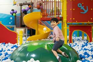 Little Asian boy looking at a floating ball Among many small balls photo