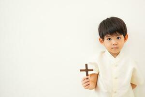 pequeño asiático chico Orando con participación el cruz, cristiano concepto foto