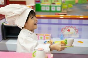 pequeño asiático chico jugando cocinero servicio comida foto