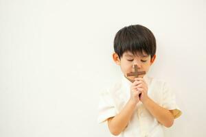 pequeño asiático chico Orando con participación el cruz, cristiano concepto foto