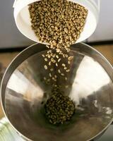 pour green beans, unroasted coffee beans into the bean hopper of the coffee roasting machine photo