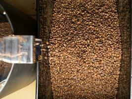 café frijoles asado proceso. muestra de Fresco café frijoles que cae desde un café asado máquina foto