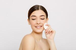 Healthy fresh girl removing makeup from her face with cotton pad. photo