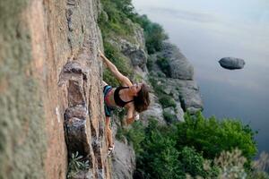 un niña sube un roca. mujer comprometido en extremo deporte. foto