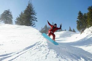 activo snowboarder saltando en montañas en un soleado día foto