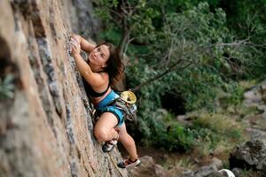 un niña sube un roca. mujer comprometido en extremo deporte. foto