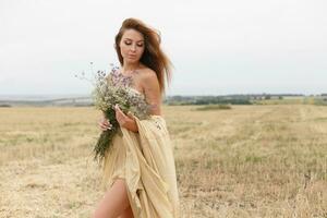 woman walking in golden dried grass field. photo