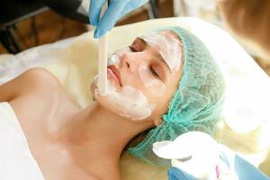 hembra cosmetóloga haciendo cosmético facial máscara a el hembra cliente foto