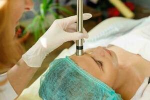 Cosmetologist makes the procedure microcurrent therapy beauty salon photo