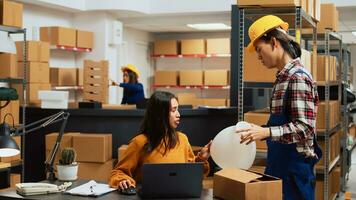 Team of asian people doing quality control on products, analyzing merchandise before packing in boxes and shipping. Small business owner and employees planning stock inventory in warehouse. photo