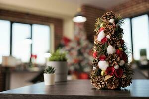 Decorated artificial christmas tree with ornaments and houseplant in festive office workplace closeup. Winter celebration season adornments in corporate workspace selective focus photo