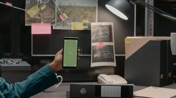 Team of police officers examining greenscreen display in private investigation room, working with chroma key template and mockup. Private detectives looking at copyspace screen. photo