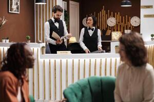 Diverse reception staff working at hotel, preparing accommodation and registration for future guests. Team of employees checking booking record files at front desk, welcome tourists. photo