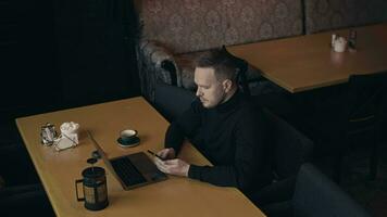 Stylish male freelancer spends time in a cafe, drinks a drink and works on a laptop. The workplace can be organized anywhere. video