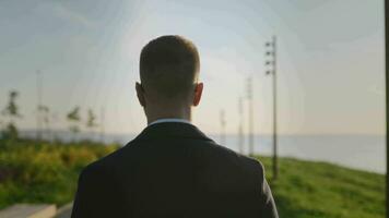 An elegant man in a stylish coat walks through a city park. Highquality public spaces are important for living and recreation in urban environments. video