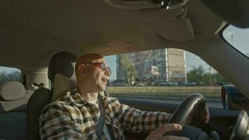 A bald middleaged man drives a rental car during a business trip or travel video