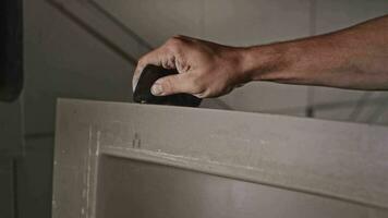 Processing the edges of a sink blank in a plumbing workshop. Closeup, hands of a working man with a scraper. video