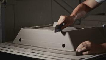 Processing the edges of a sink blank in a plumbing workshop. Closeup, hands of a working man with a scraper. video