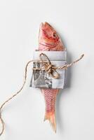 Salt-dried red mullet wrapped in newspaper and tied with thread on white background photo